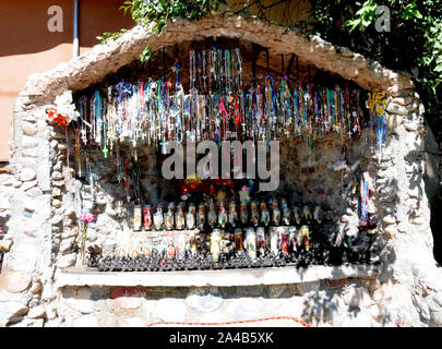 Angebote der Kruzifixe und Kerzen in einer kleinen künstlichen Grotte bei El Santuario De Chimayo, New Mexico. Die Kirche und die Anlage ist ein Bereich der Wallfahrt Stockfoto