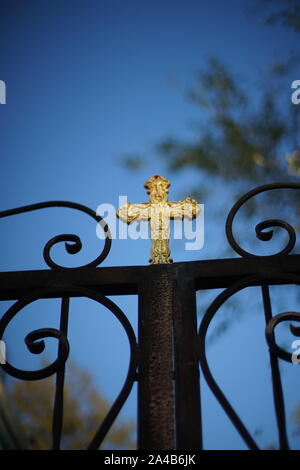 Schwarz geschmiedeter Zaun mit einem goldenen Kreuz Stockfoto