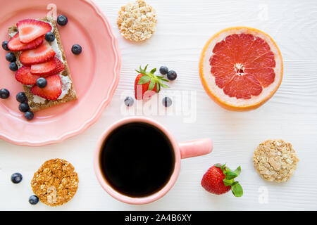 Gesundes Frühstück mit Obst, leckere Toast und frischen Kaffee schwarz auf weiß Tisch, flach. Stockfoto