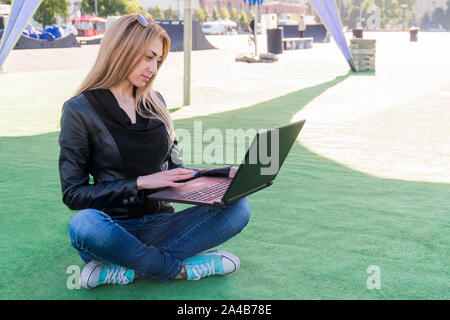 Frau mit einem Notebook auf dem Gras Stockfoto