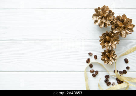 Golden Pine Cones (lackierte Tannenzapfen) mit gerösteten Kaffeebohnen und goldenen Band auf weißem Hintergrund, Ansicht von oben, kopieren. Weihnachten backgroun Stockfoto