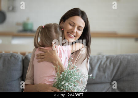Glücklich lächelnde Mutter umarmen kleine Tochter, zu danken für das Geschenk, Stockfoto