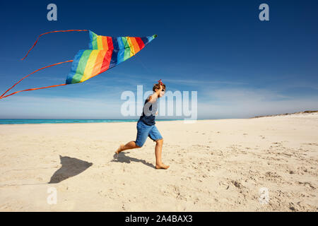 Süße Junge, Lauf mit Farbe Kite am Sandstrand Stockfoto