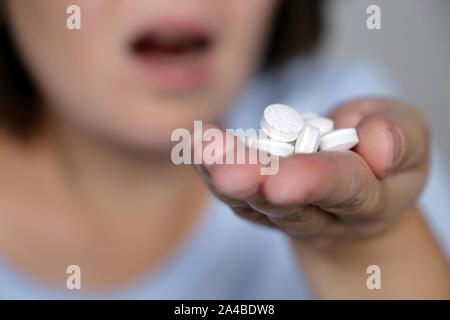 Mädchen nehmen Pillen, weiblichen Palme der Hand weiße Tabletten. Kranke Frau, Konzept der Überdosierung von Medikamenten, Antibiotika, Schmerzmittel oder Vitamine Stockfoto