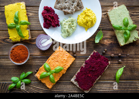 Verschiedene Arten von Hummus auf weiße Platte und gesundes Brot auf braune Holztisch. Helle Farben essen. Stockfoto