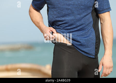 Nahaufnahme eines Sportlers Hand kneifen Körperfett im Freien am Strand Stockfoto