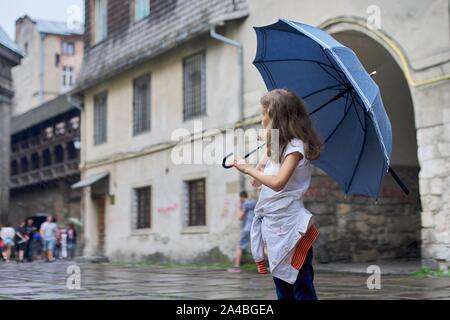 Kleine Mädchen im Regen mit einem Schirm, touristische Altstadt Hintergrund Kopie Raum Stockfoto