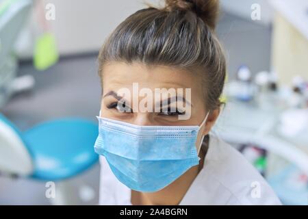 Closeup Portrait von lächelnd weibliche Zahnarzt Arzt in schützende medizinische Maske am Arbeitsplatz zahnmedizinische Klinik Büro, positiven Gesicht Stockfoto