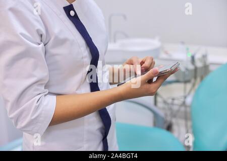 In der Nähe der weiblichen Ärzte hand mit Handy Smartphone, zahnmedizinische Klinik Büro Hintergrund Stockfoto