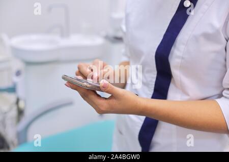 In der Nähe der weiblichen Ärzte hand mit Handy Smartphone, zahnmedizinische Klinik Büro Hintergrund Stockfoto