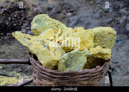 Blöcke von Schwefel in einem Korb, aus vulkanischem gas Lüftungsschlitze in die Kiste des Mount Ijen, Ost Java, Indonesien abgebaut. Gase sind durch Leitungen umgeleitet und die Stockfoto