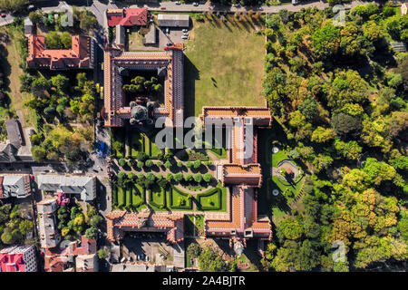 Wundervolles, altes Gebäude der Czernowitzer Universität mit Türmen und Kuppeln zwischen grünen Bäume und Häuser in der Ukraine. Sonne scheint auf Sie. Ansicht von oben Stockfoto