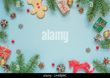 Weihnachten Komposition. Rahmen aus Tanne Baum verzweigt, Dekorationen, Beeren, Lebkuchen und Tannenzapfen auf blauem Hintergrund. Weihnachten Hintergrund. Fla Stockfoto