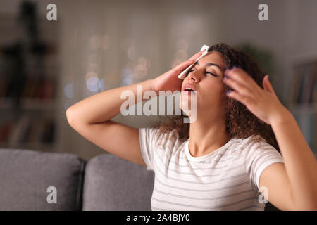 Betonte Frau trocknen schwitzen Sie in einer warmen Nacht auf einer Couch im Wohnzimmer zu Hause sitzen Stockfoto