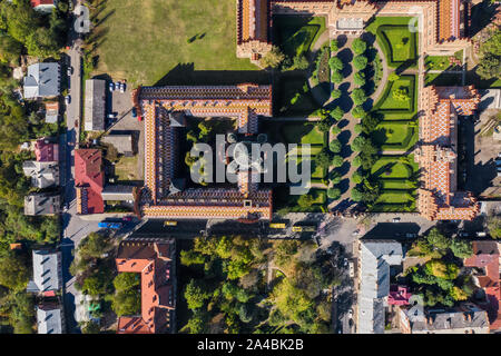 Historische Gebäude der Czernowitzer Universität mit Türmen und Kuppeln zwischen grünen Bäume und Häuser in der Ukraine. Sonne scheint auf Sie. Top vie Stockfoto