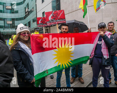 London, Großbritannien. 13. Oktober 2019. Kurden halten die kurdische Fahne vor der BBC. Kurden treffen außerhalb der BBC und eine Rallye mit Reden von einem kurdischen Bürgermeister, anderen Kurden und der britische Gewerkschafter halten, bevor sie durch London marschieren aus Protest gegen die türkische Invasion im Nordosten Syriens. Sie sehen die Türkische Offensive als Versuch der freien ISIS Kämpfer und ethnisch zu Kurden aus Rojava, der ruhigsten Gegend von Syrien, eine kurdische Reinigen - LED-Demokratie engagierten, die Befreiung der Frauen und ökologische Gerechtigkeit. Peter Marshall / alamy Leben Nachrichten Stockfoto