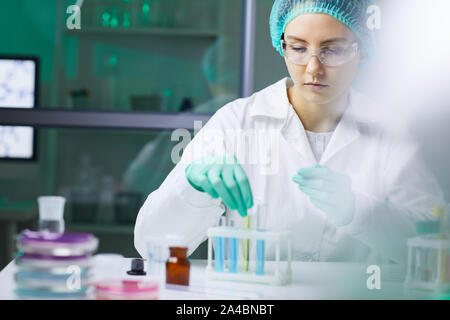 Porträt der jungen Frau, die Reagenzglas mit farbige Flüssigkeit während auf Forschung im medizinischen Labor arbeiten, kopieren Raum Stockfoto