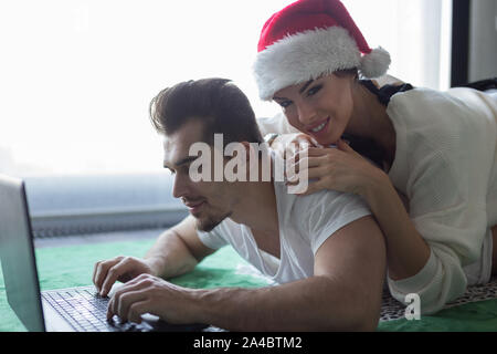 Glückliches junges Paar casucasian Online Shopping auf dem Teppich für Weihnachten Stockfoto