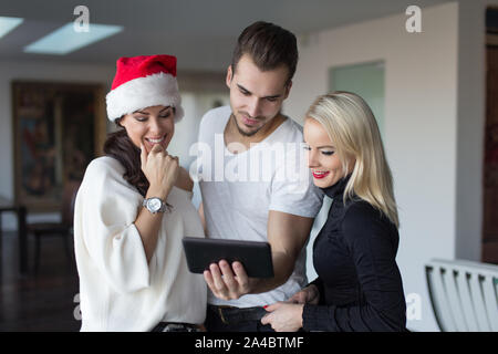Glückliche junge aufgeregt Freunde online Einkaufen für Weihnachten zu Hause Stockfoto
