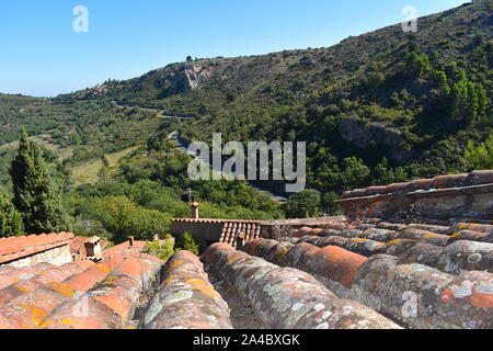 Braun, Rot, Orange und Gelb französischen Dachziegeln und Schornsteine mit Blick auf Gebirgsstrasse umgeben von Grün. Malerische Self Drive Urlaub. Stockfoto