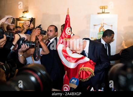 Tunis, Tunesien. 13 Okt, 2019. Tunesien der unabhängige Präsidentschaftskandidat Kais Saied (R, vorne) Küsse eine tunesische nationale Flagge während einer Pressekonferenz in Tunis, Tunesien, am Okt. 13, 2019. Kais Saied angekündigt Sonntag Abend, dass er die zweite Runde der Präsidentschaftswahlen gewonnen. Credit: Wu Huiwo/Xinhua/Alamy leben Nachrichten Stockfoto