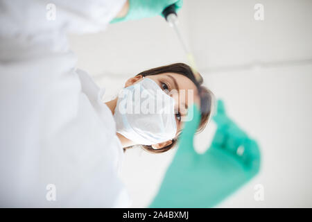 Low Angle Portrait von Ärztin durch das Tragen von schützender Maske im medizinischen Labor Stockfoto
