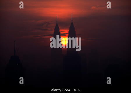 Kuala Lumpur, Malaysia. 14 Okt, 2019. Die Sonne steigt aus der Richtung zwischen den Petronas Twin Towers in Kuala Lumpur, Malaysia, Okt. 14, 2019. Credit: Chong Voon Chung/Xinhua/Alamy leben Nachrichten Stockfoto