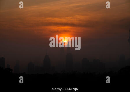 Kuala Lumpur, Malaysia. 14 Okt, 2019. Die Sonne steigt aus der Richtung zwischen den Petronas Twin Towers in Kuala Lumpur, Malaysia, Okt. 14, 2019. Credit: Chong Voon Chung/Xinhua/Alamy leben Nachrichten Stockfoto