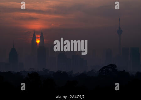 Kuala Lumpur, Malaysia. 14 Okt, 2019. Die Sonne steigt aus der Richtung zwischen den Petronas Twin Towers in Kuala Lumpur, Malaysia, Okt. 14, 2019. Credit: Chong Voon Chung/Xinhua/Alamy leben Nachrichten Stockfoto