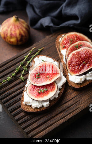 Roggen Toast mit ricotta Käse und Feigen auf Holz Schneidebrett. Gesunde Snack Stockfoto