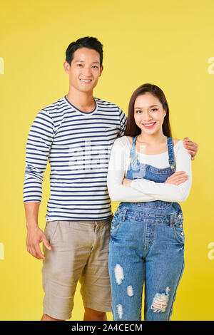 Positive jungen vietnamesischen Mann ist gestreiften Hemd umarmte seine hübsche Freundin tragen Denim insgesamt Stockfoto