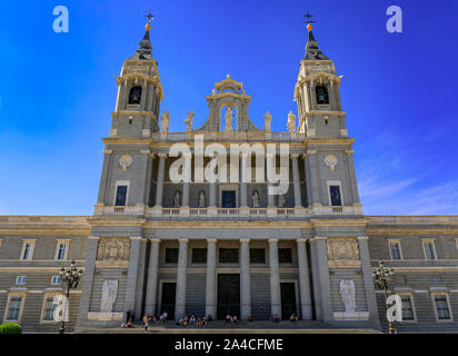 Madrid, Spanien - 4 Juni, 2017: Hauptfassade der Kathedrale Unserer Lieben Frau von LaAlmudena durch den Königspalast mit Menschen sitzen auf den Stufen Stockfoto