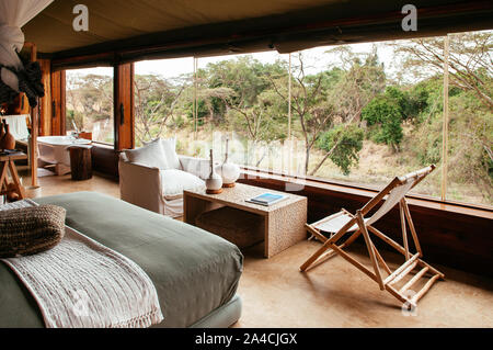 JUN 20, 2011 Tansania - Afrika - asain Boho zeitgenössische Zelt Camp Lodge Schlafzimmer Innenraum mit Naturholzmöbeln und weiche Bett mit Fore Stockfoto