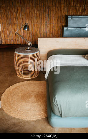 JUN 20, 2011 Tansania - Afrikanische Boho, moderne Haus Schlafzimmer Innenraum mit Rattan Beistelltisch, moderne Lampe, weiche Bett und Bambus Wand. Stockfoto