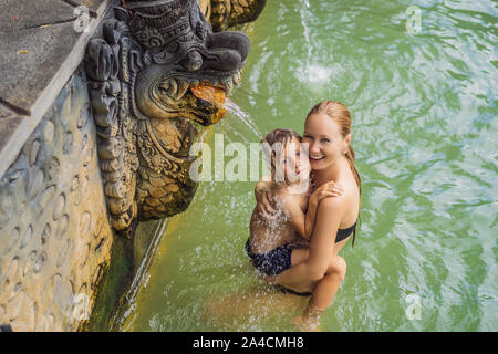 Mutter und Sohn Reisende in heißen Quellen von Banjar. Das Thermalwasser wird aus dem Mund von Statuen an einem heißen Quellen von Banjar, Bali, Indonesien freigegeben Stockfoto