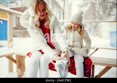 Familie in Winter Park. Mutter mit Tochter in einem Ice Arena. Mama legt ihre Tochter in Skates Stockfoto