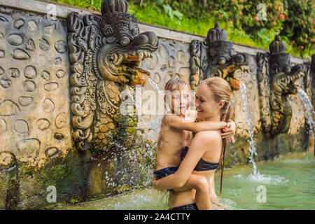 Mutter und Sohn Reisende in heißen Quellen von Banjar. Das Thermalwasser wird aus dem Mund von Statuen an einem heißen Quellen von Banjar, Bali, Indonesien freigegeben Stockfoto