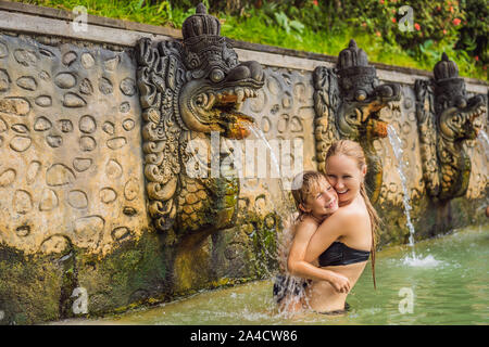 Mutter und Sohn Reisende in heißen Quellen von Banjar. Das Thermalwasser wird aus dem Mund von Statuen an einem heißen Quellen von Banjar, Bali, Indonesien freigegeben Stockfoto