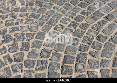 Gepflasterte Straße zu schließen. Fußgängerzone ebnet in der Straße. Gepflastert, Detail. Braune Textur einer Pflasterstein Spur auf einer Sand. Stockfoto