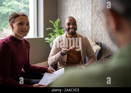 Kreative afrikanischen Geschäftsmann lächelnd und Plaudern zwanglos mit anderen verschiedenen südafrikanischen Kollegen Stockfoto