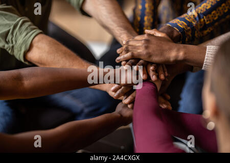 7/8 in der Nähe diverser Geschäftsleute die Hände übereinander legere Kleidung und afrikanischen Mustern. Stockfoto