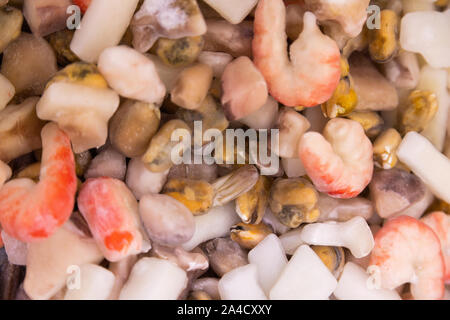 Verschiedene frozen Seafoods alle zusammen in einem Stapel, wahrscheinlich im Supermarkt. Bunte rohe Garnelen flatlay. Stockfoto