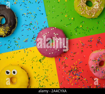 Runde Donuts mit verschiedenen Füllungen und Streuseln auf eine abstrakte Farbe Hintergrund mit festlichen Dekor Stockfoto