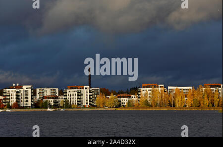 Ein Blick auf die Stadt mit weißen Häusern und gelbe Birken. Himmel ist dunkel blau mit Regen Stockfoto