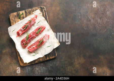 New York Strip Steak mit Salz und Rosmarin auf dunklem Hintergrund, Ansicht von oben, kopieren. Auch rohes Rindfleisch strip Steaks. Stockfoto