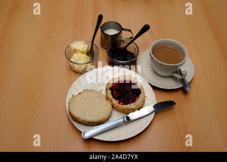 Traditioneller Nachmittagstee mit großen Scone in zwei Hälften schneiden, mit himbeermarmelade auf einer Hälfte Stockfoto