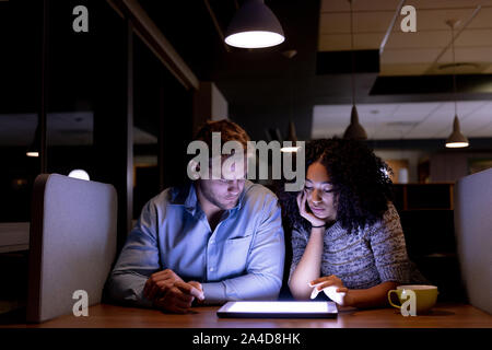 Zwei junge kreative Fachleute, die spät in einem modernen Büro Stockfoto