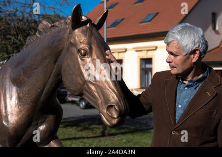 Zamrsk, Tschechische Republik. 12 Okt, 2019. Tschechische Bildhauer Petr Novak berührt die Bronzestatue von peruan Race Horse in Zamrsk, Tschechische Republik, 12. Oktober 2019. Peruan gewann den Grand Pardubitzer Steeplechase dreimal und seine Statue außerhalb der Pferderennen in Zamrsk vorgestellt wurde am Vorabend der Hindernislauf. Peruan wurde auf einem Bauernhof in Zamrsk ausgebildet, er lebte und starb dort 2017. Quelle: David Tanecek/CTK Photo/Alamy leben Nachrichten Stockfoto