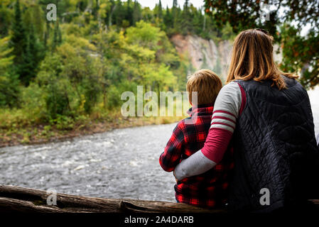 Mutter und Sohn sitzen auf einem Baumstamm in Aussicht suchen, United States Stockfoto