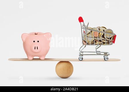 Piggy Bank und Warenkorb mit Münzen auf Balance Skala Stockfoto